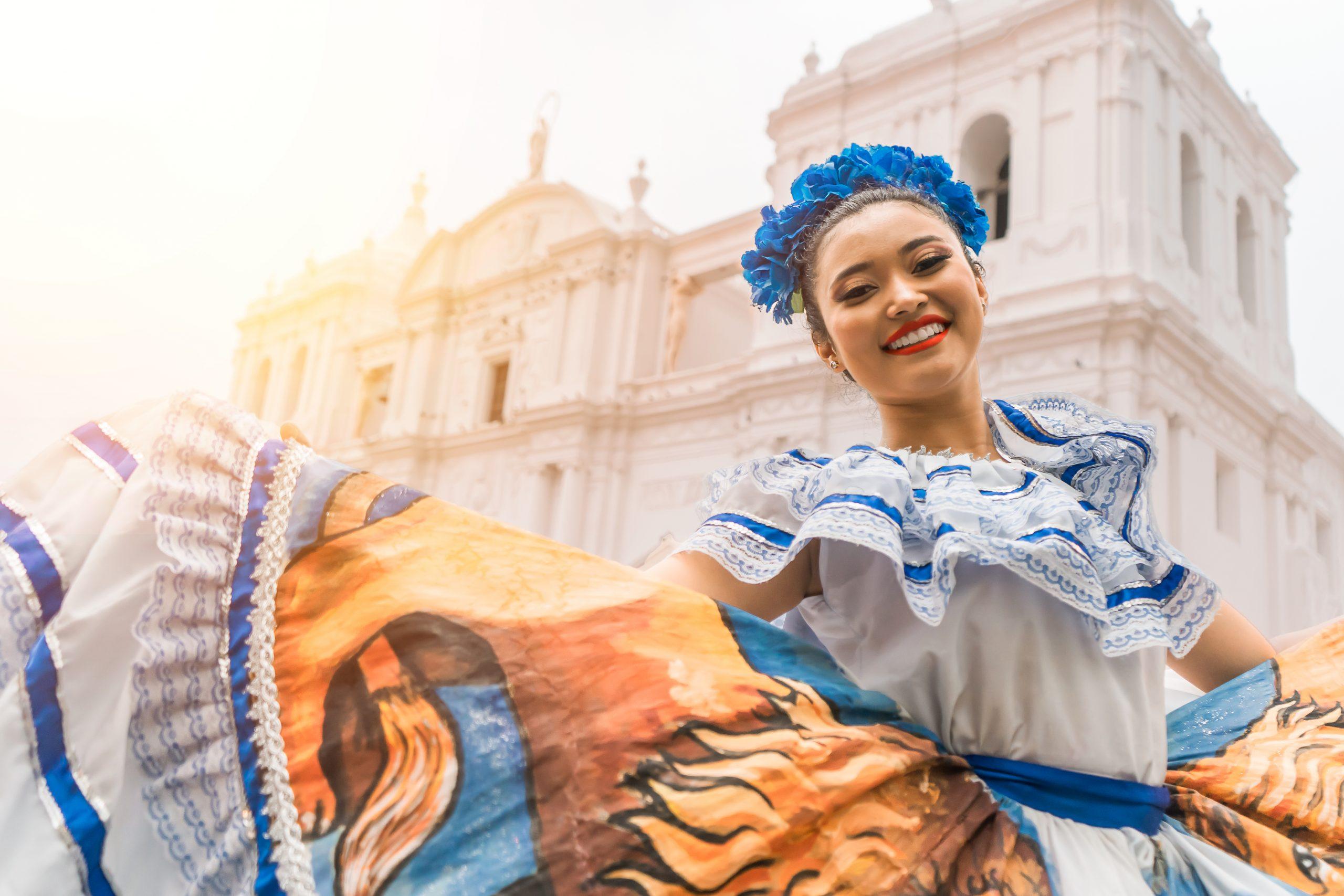 Nicaraguan folklore dancer smiling and looking at the camera outside the cathedral church in the central park of the city of Leon. The woman wears the typical dress of Central America and similar to countries of South America