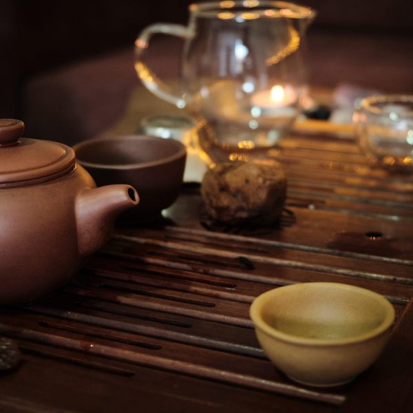 Traditional chinese tea ceremony utensils on a tea tray. Chinese teapots made of brown yixing clay and glass and cups. Tea brewing equipment low key dark mood